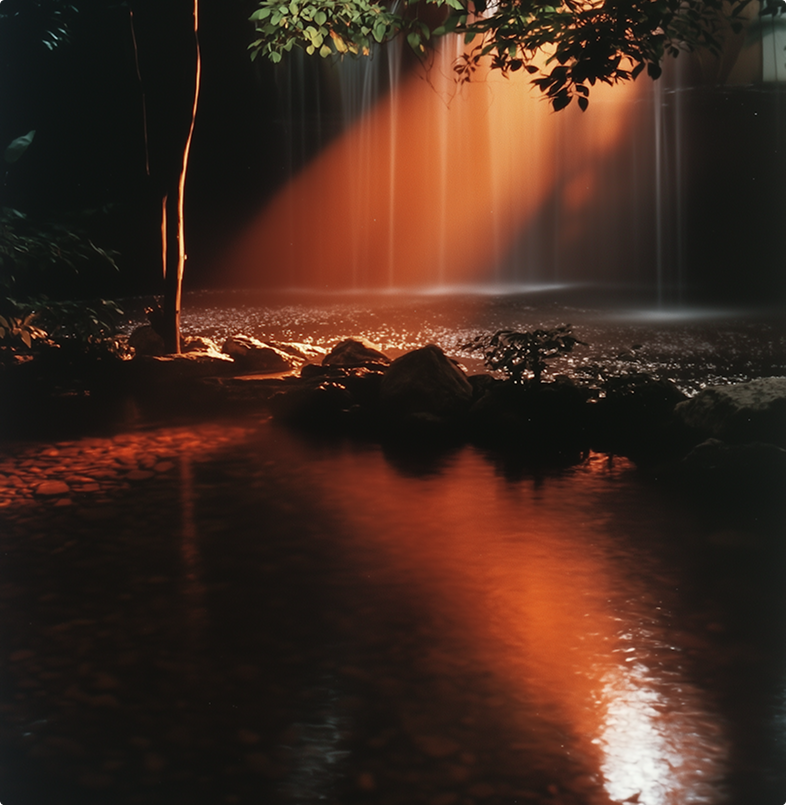 Small waterfall lit by a warm orange beam in a dark lush setting