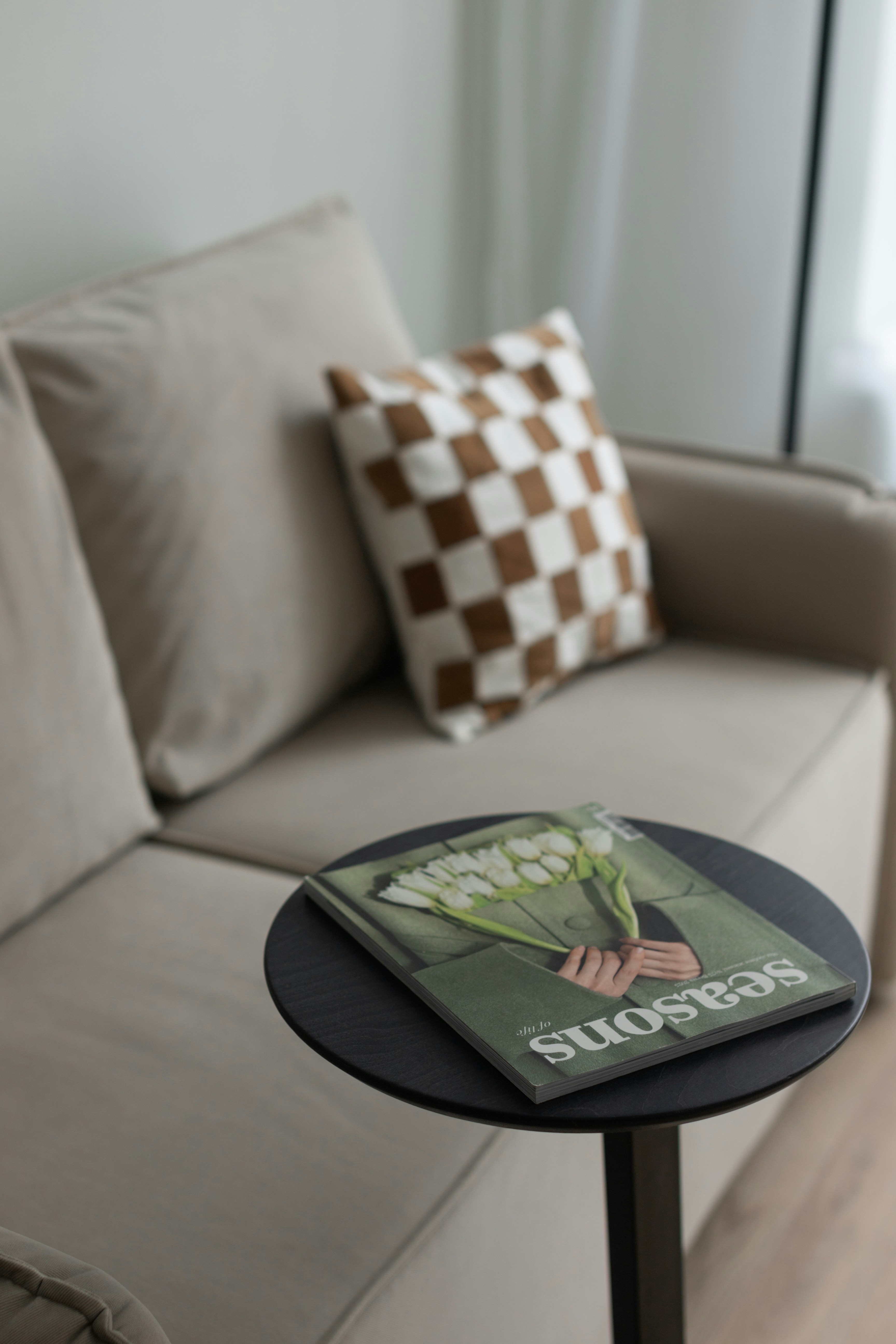 Seasons of life magazine on a round side table beside a beige sofa